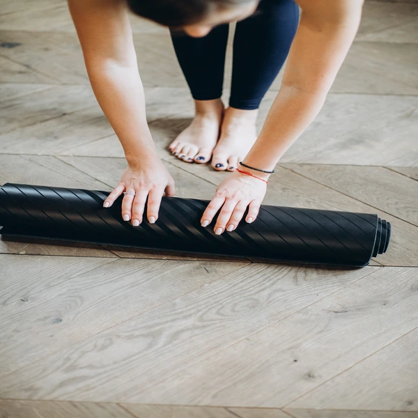 person rolling a yoga mat
